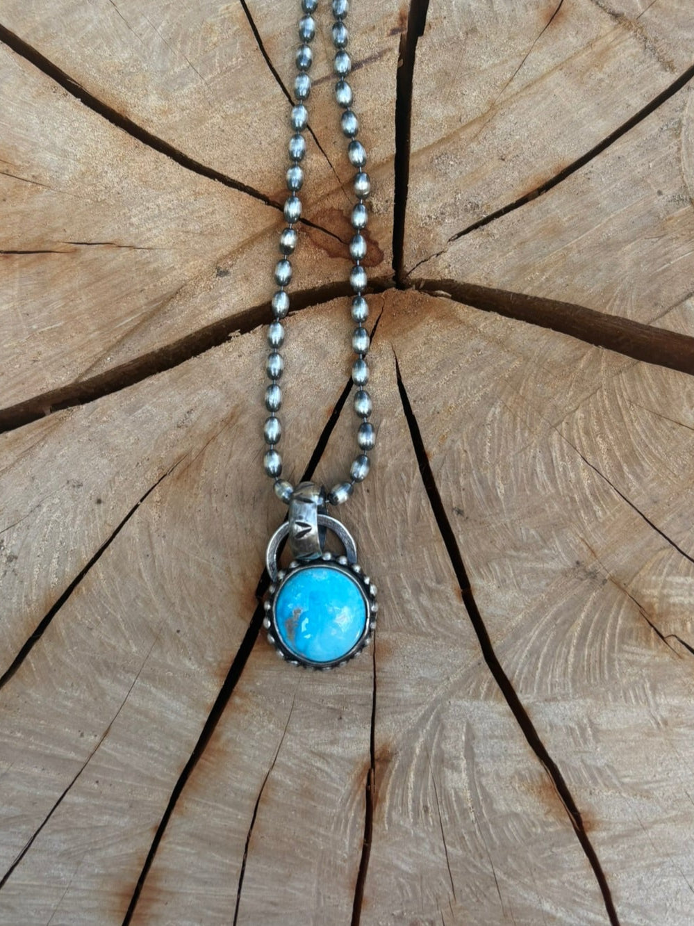 Necklace with a blue pendant on a wooden stump