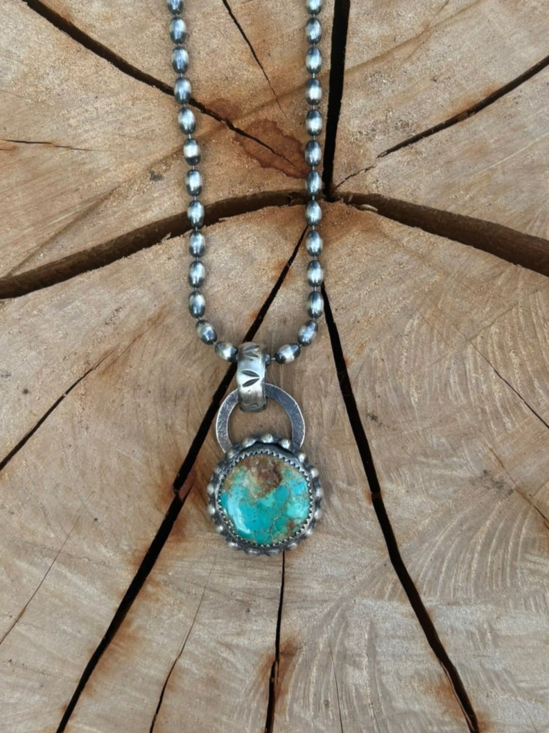 Necklace with a turquoise pendant on a wooden stump