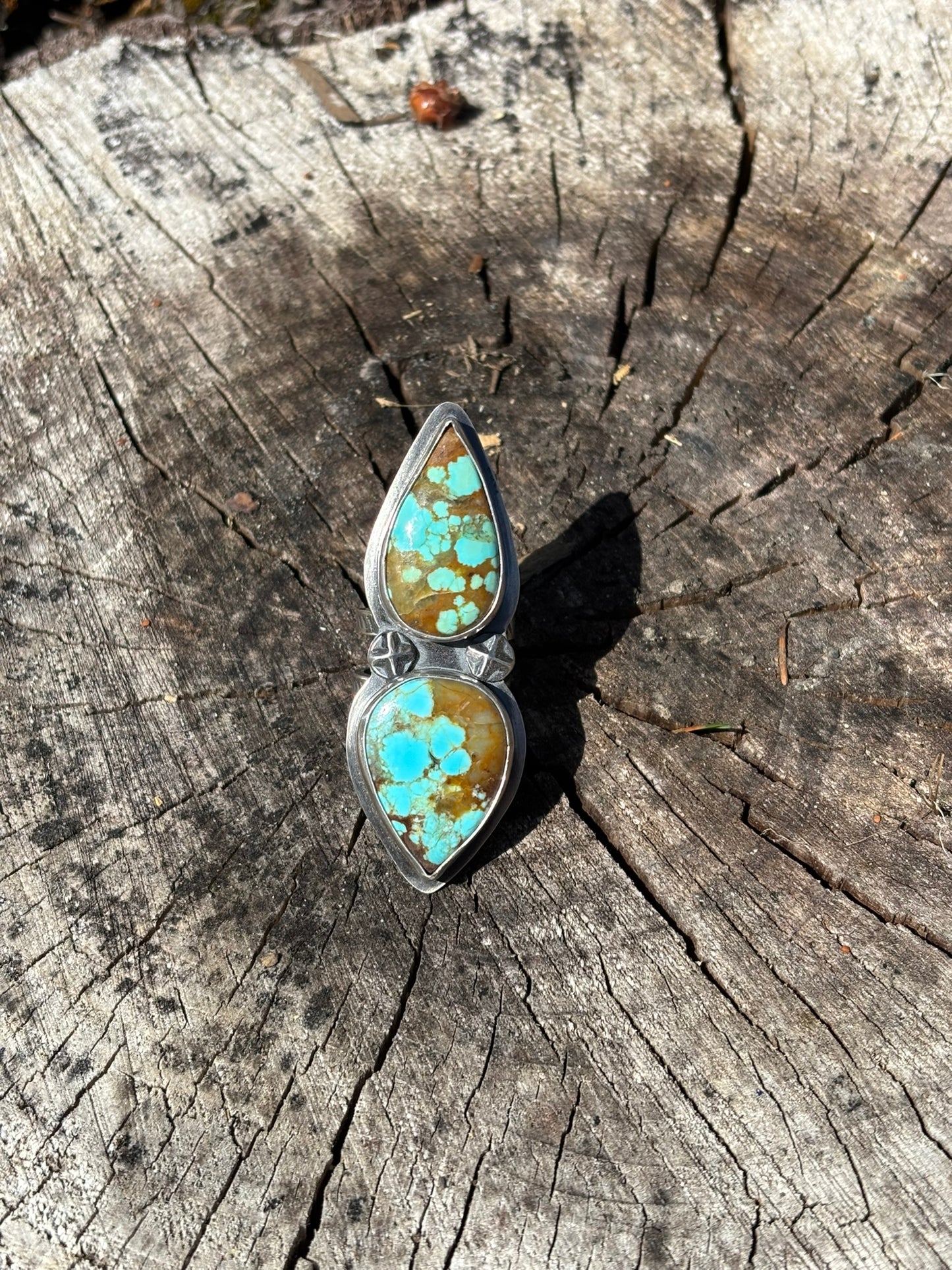 handmade turquoise and silver ring with 2 teardrop stones and 2 star shaped silver shots on wood round
