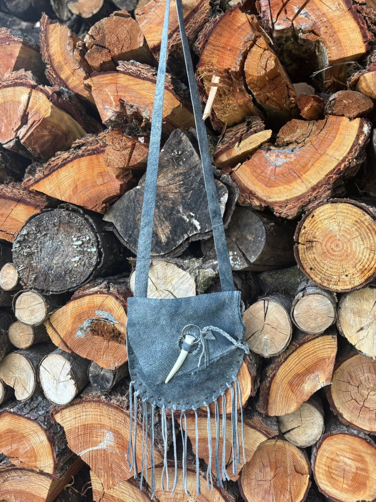Blue handbag with fringe on a stack of wooden logs