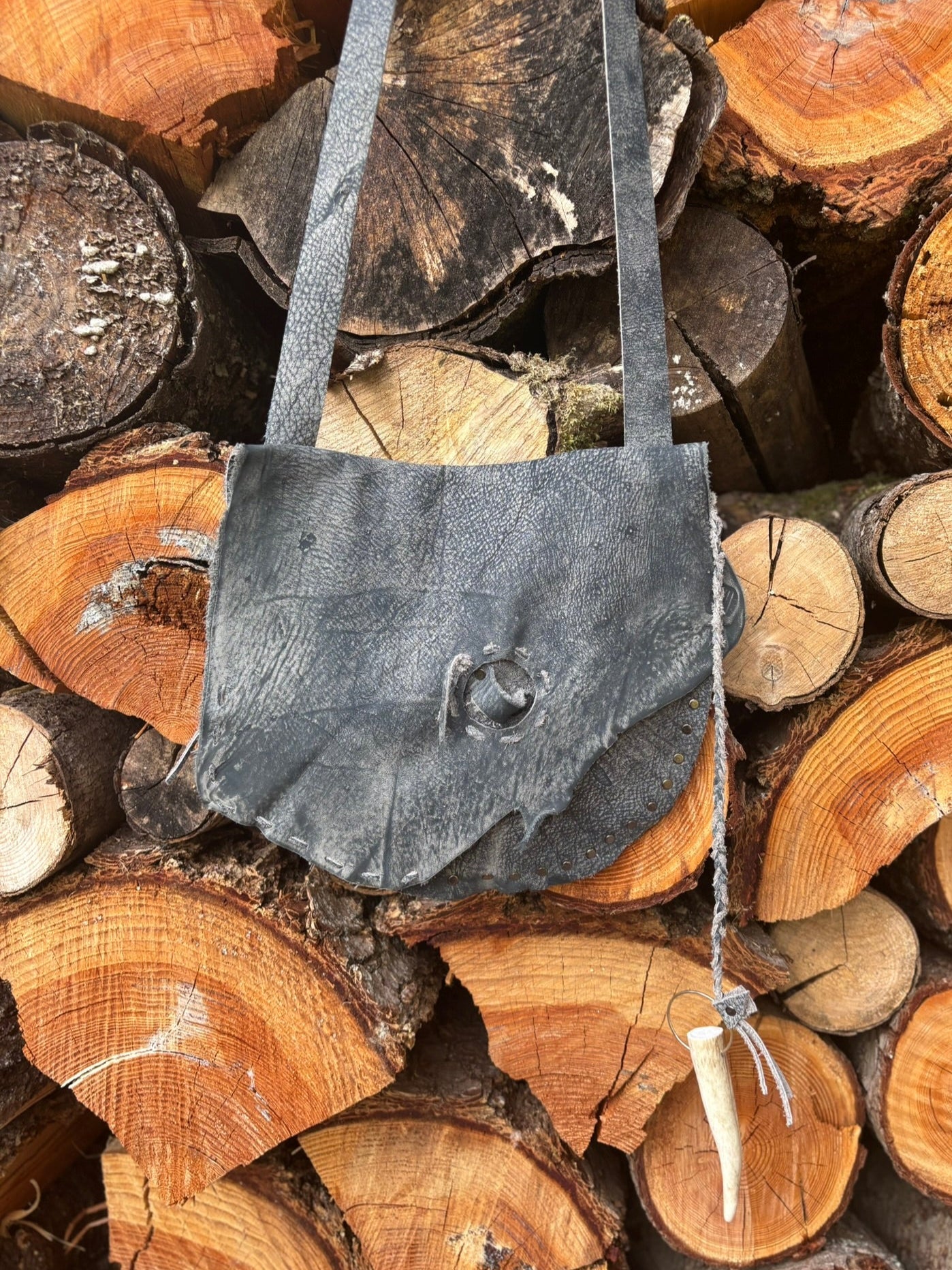 leather bag on a stack of wooden logs