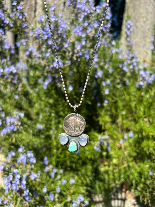 buffalo nickel, opalite, and turquoise pendant on a silver ball chain in the sun with rosemary background