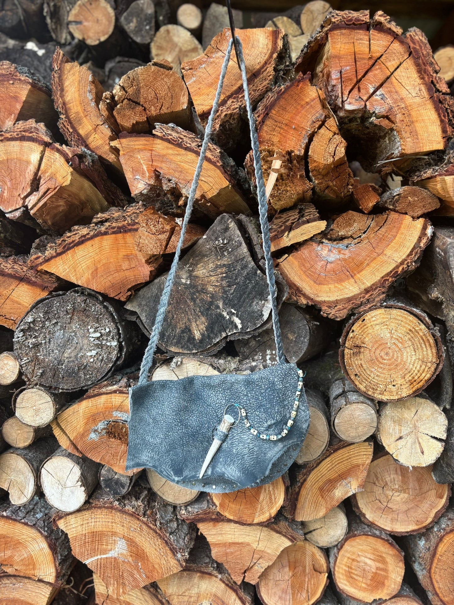Small blue bag with a strap on a pile of wooden logs