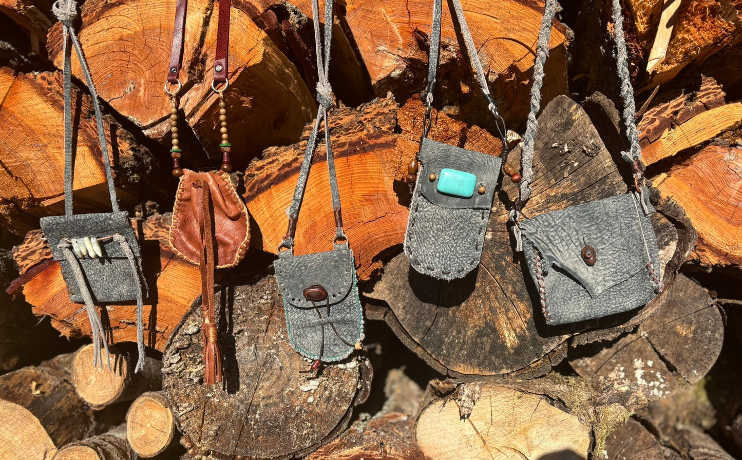 Small leather bags hanging on a stack of wooden logs