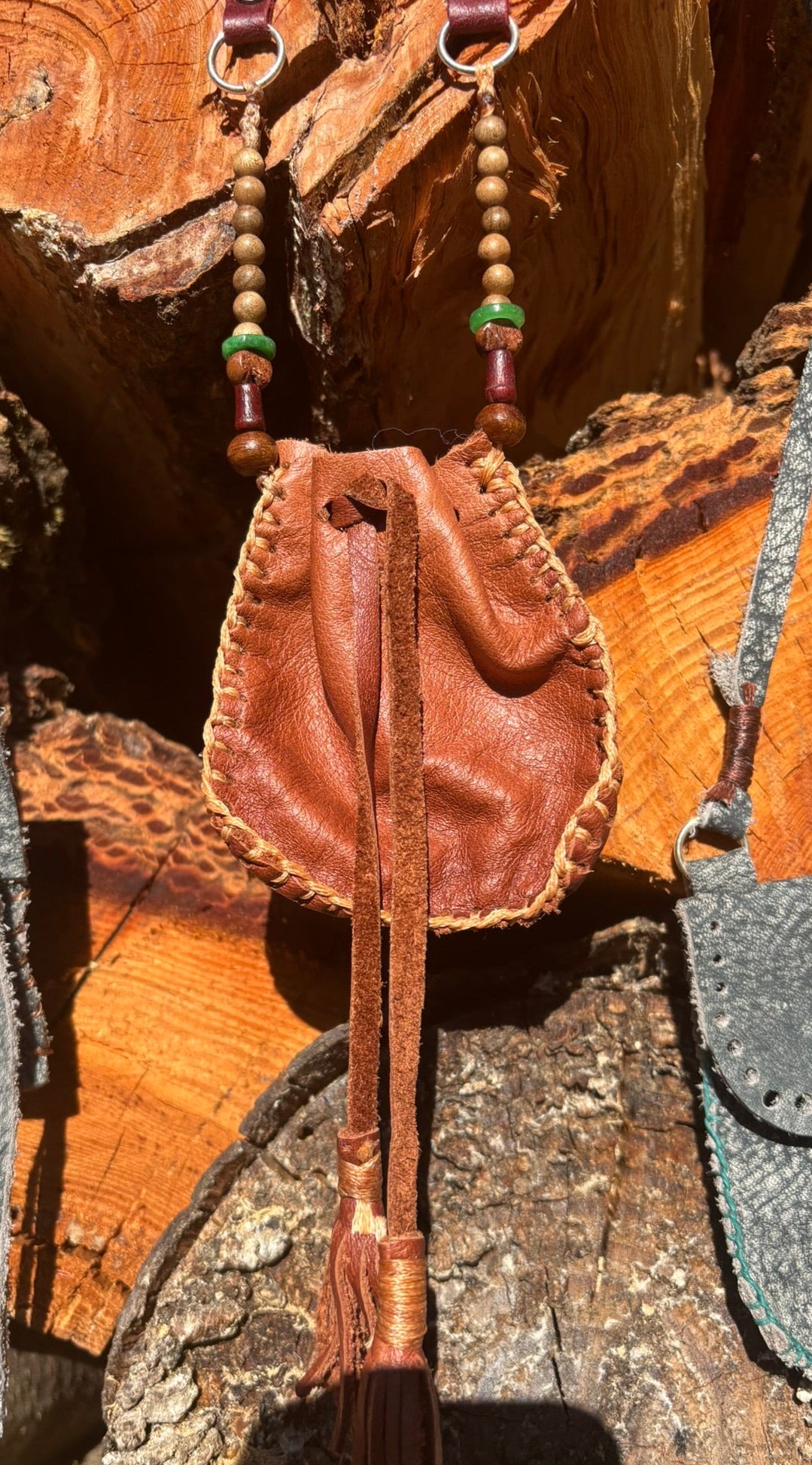 Brown leather drawstring bag with tassel on a wooden surface