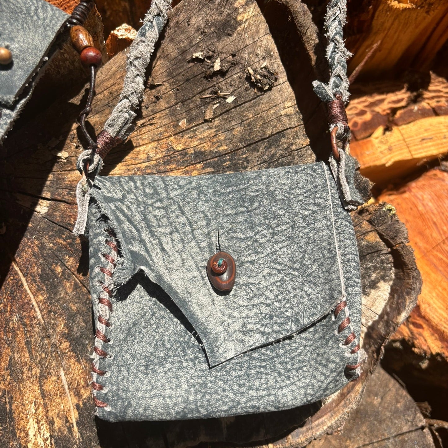 Small gray leather bag with brown leather trim on a wooden surface
