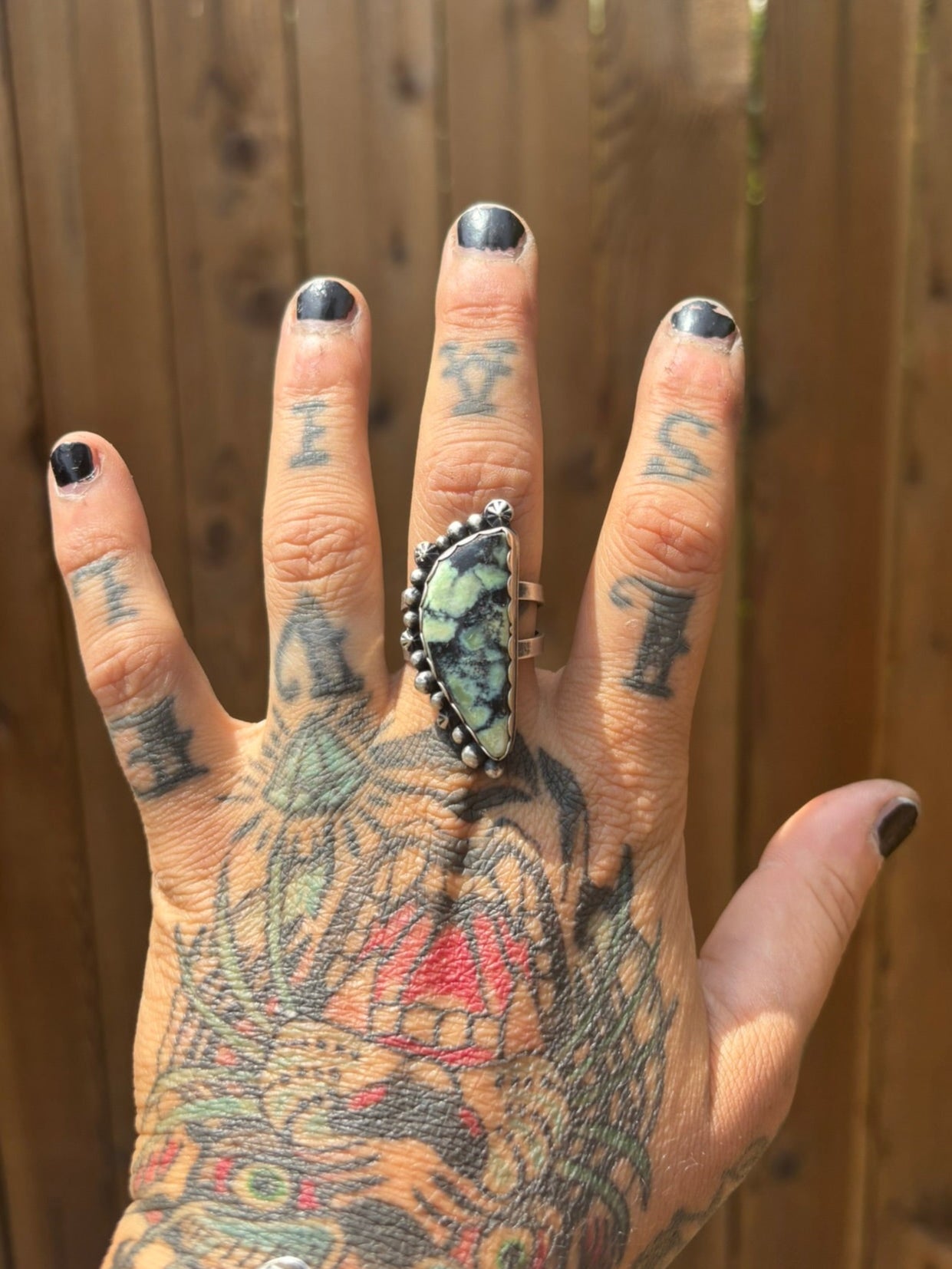 handmade silver and variscite stone ring, half moon shape stone and lots of shots and stars along the curve with a double silver band and signed on the backplate, shown on a tattooed hand with black nail polish