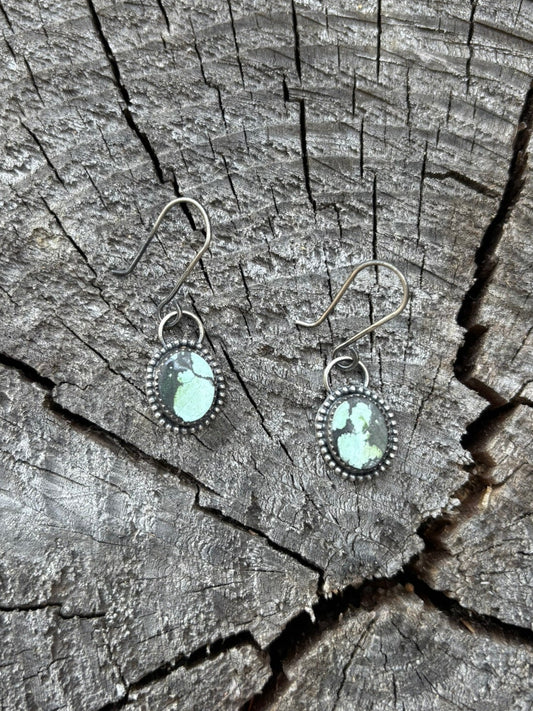 handmade turquoise earrings on a wood round stump