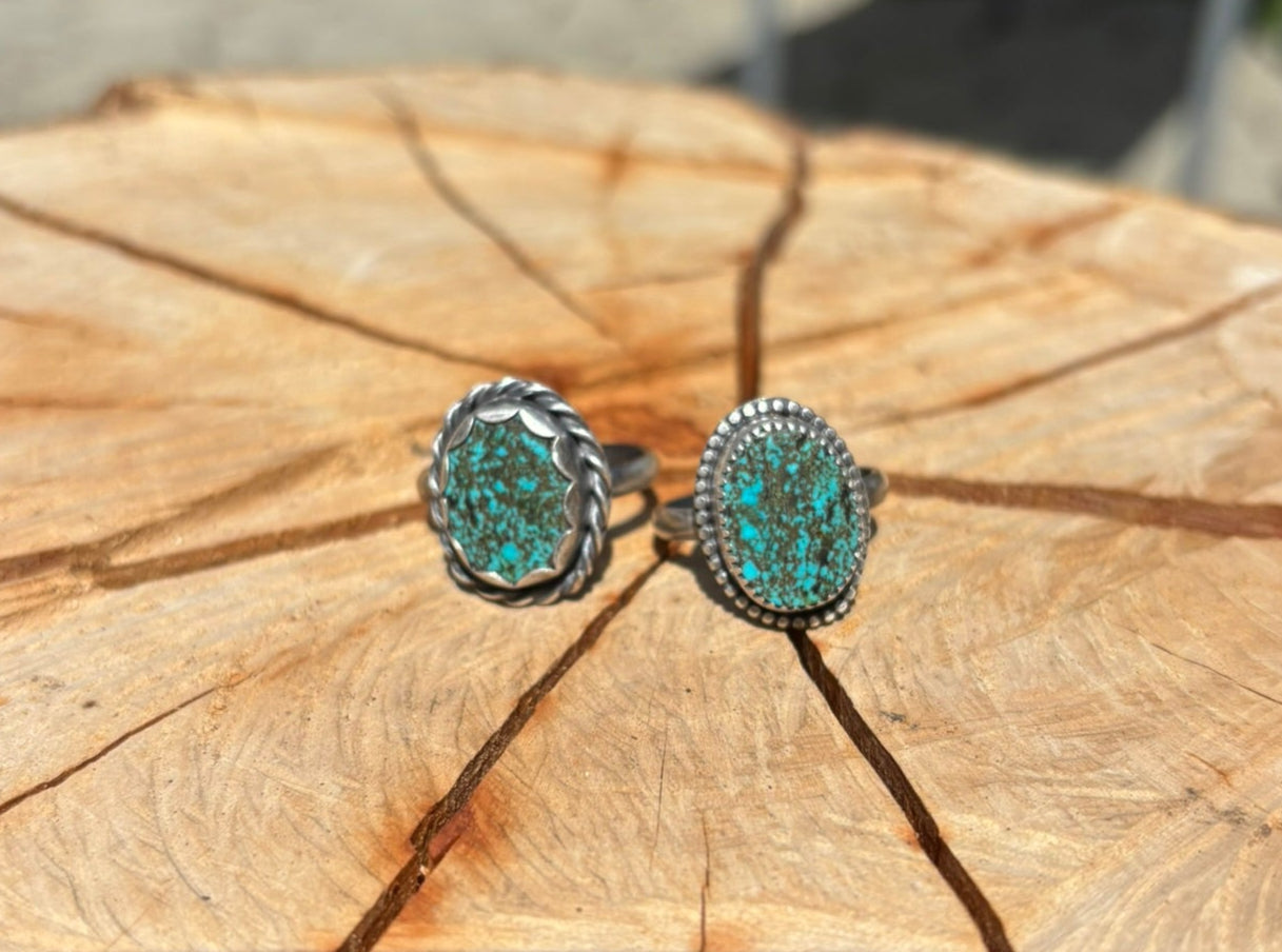 Turquoise rings on a wooden surface with a blurred outdoor background