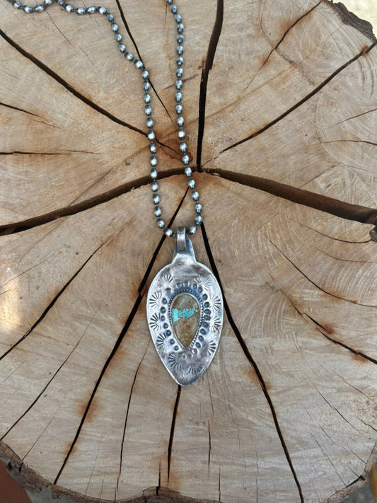 Silver pendant with chain on a wooden surface