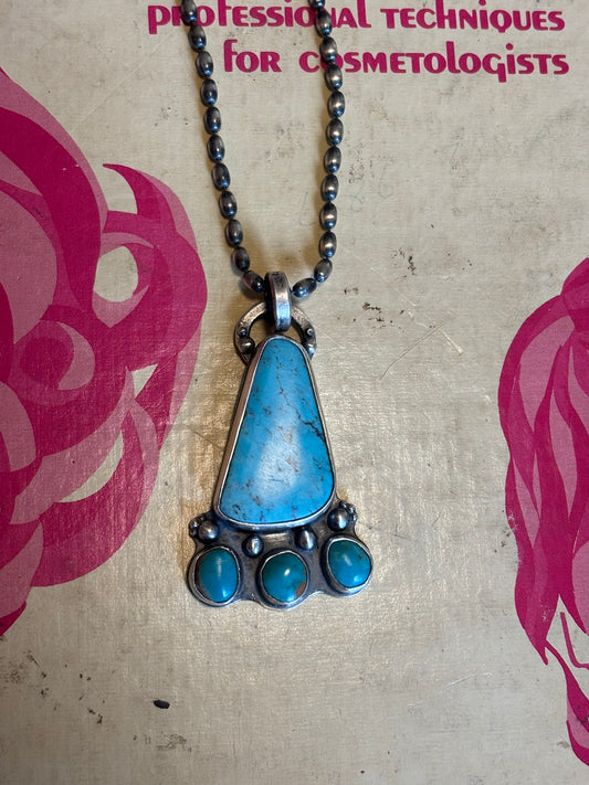 Necklace with a blue pendant on a textured surface with text