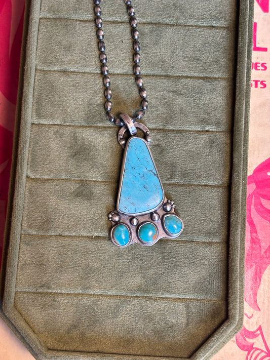 Necklace with a turquoise pendant on a textured surface