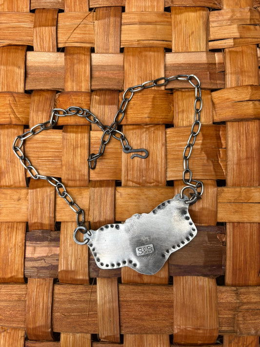 backside view of handmade turquoise and silver necklace with handmade chain and clasp on wood round