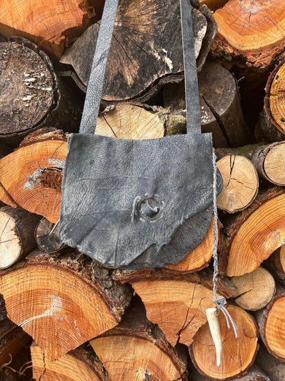 leather bag on a stack of wooden logs
