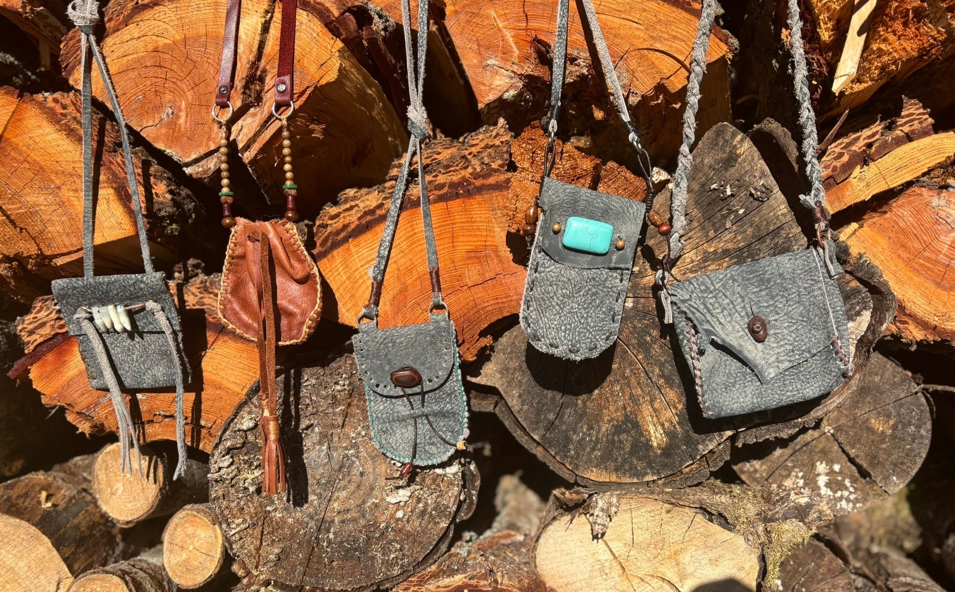 Small leather bags hanging on a stack of wooden logs