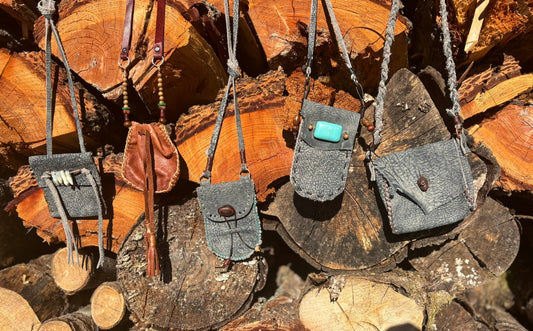 Small leather bags hanging on a stack of wooden logs