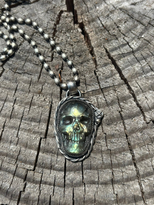 labradorite skull pendant made with silver twist wire and silver shot details and a half round silver wire bail, medium size to accommodate a medium to large chain size shown on ball chain atop a wood stump