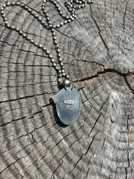 back view of a skull pendant made from carved labradorite set in fine and sterling silvers, stamped artist signature on back and hung on large silver ball chain