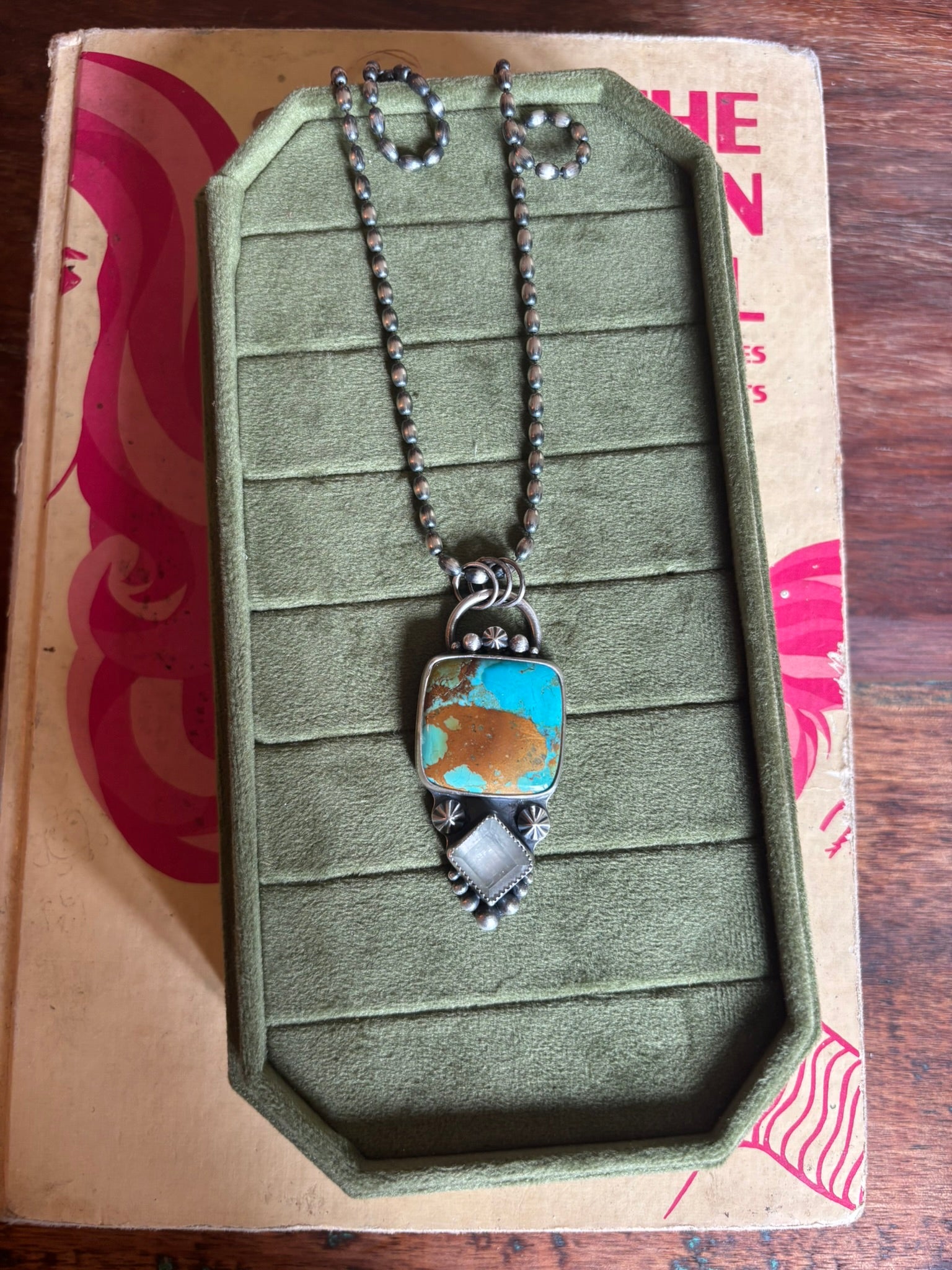Necklace with a pendant on a green jewelry display box