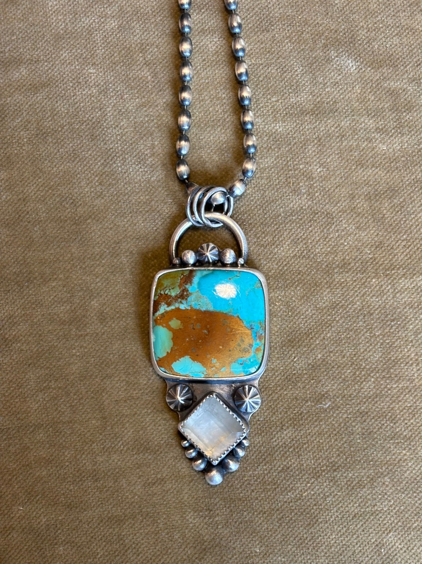 Necklace with a square turquoise pendant on a beige background