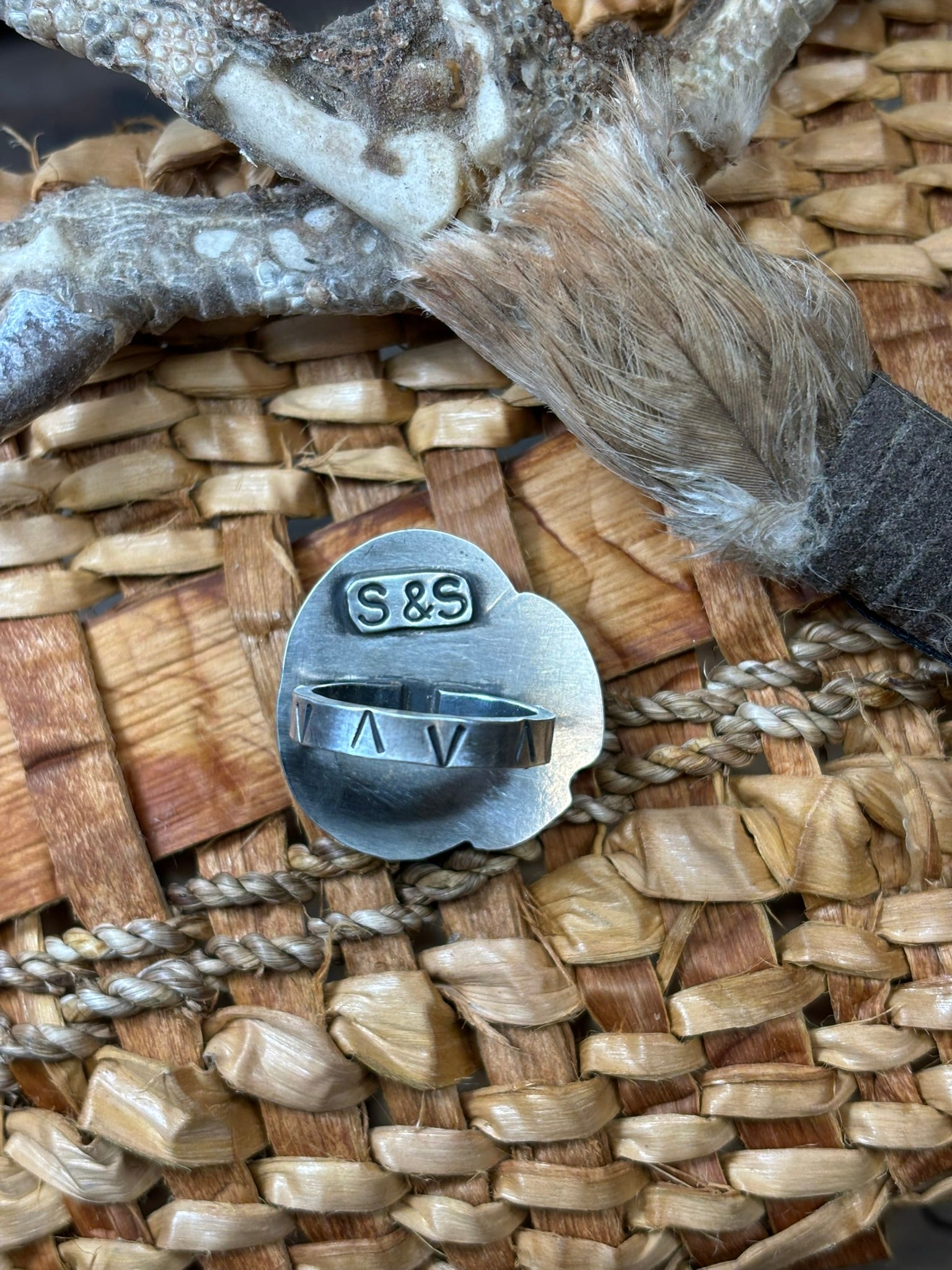 back side of turquoise and feathers ring showing hand stamped band and artist stamp signature on the backplate