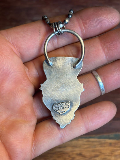Silver keychain with 'S&S' initials held in a hand on a wooden surface