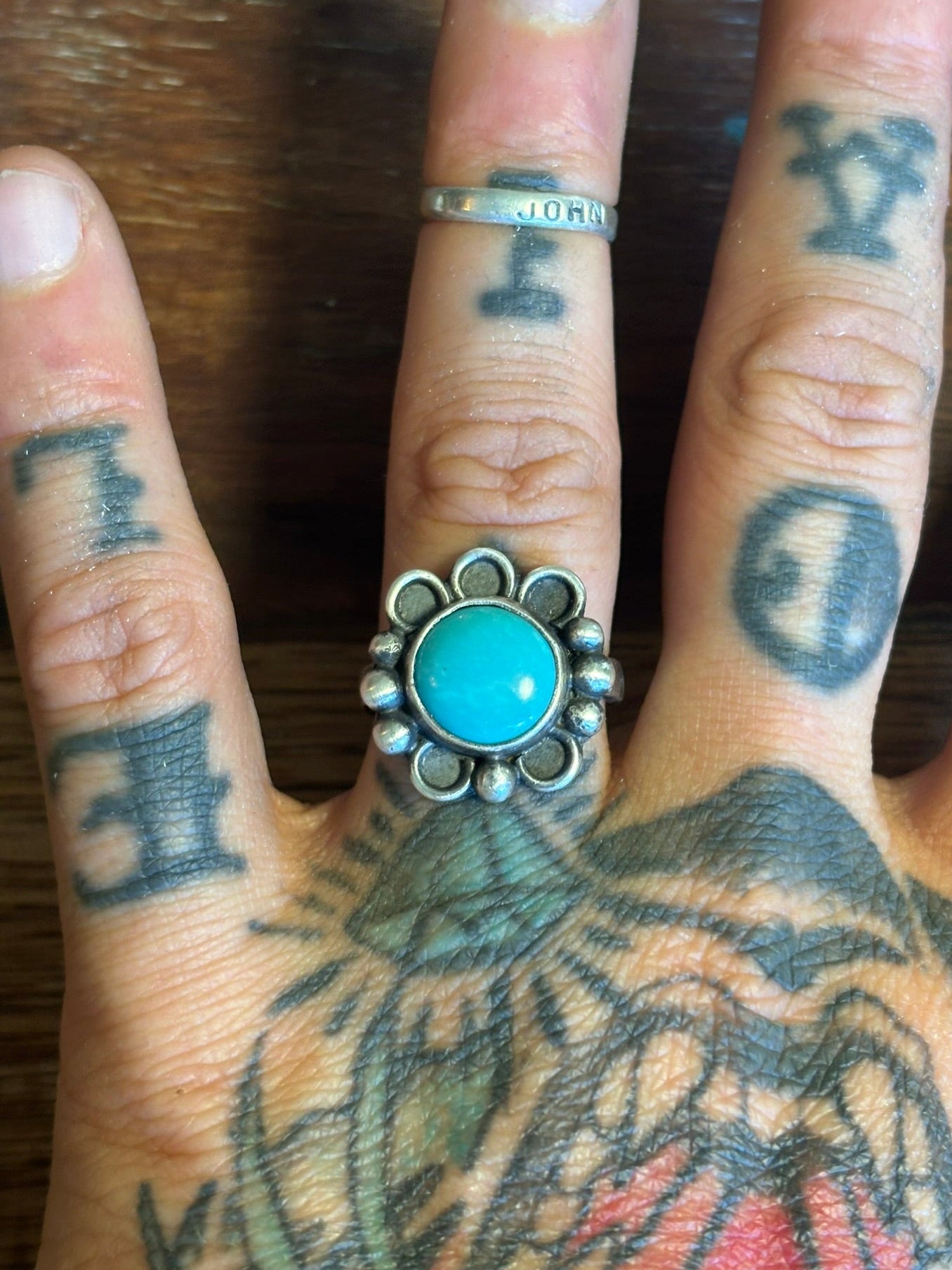 Hand with turquoise stone ring on a wooden surface