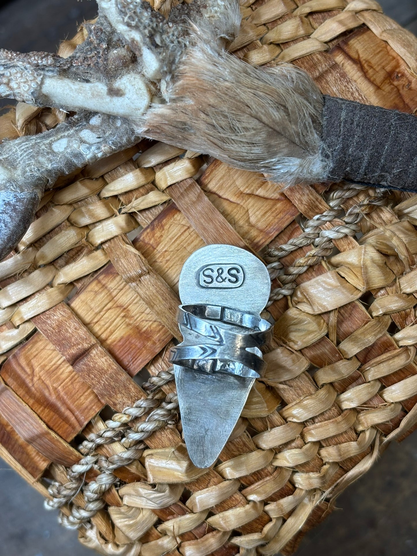 back view of handmade variscite & arrowhead ring, showing double band, hand stamped details and artists signature on backplate. placed on handmade cedar basket