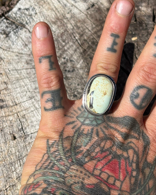 seafoam yellow/green variscite stone set in fine and sterling silvers with stamped border details and single band in size 8 worn on ring finger of left tattooed hand